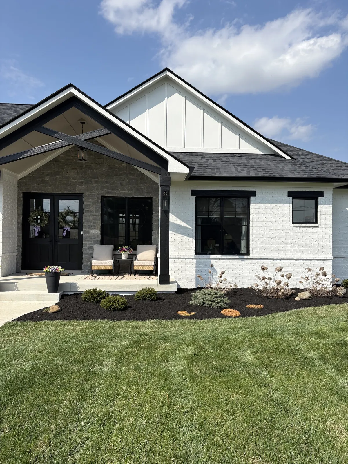 Fresh black mulch along the front of a white farmhouse.